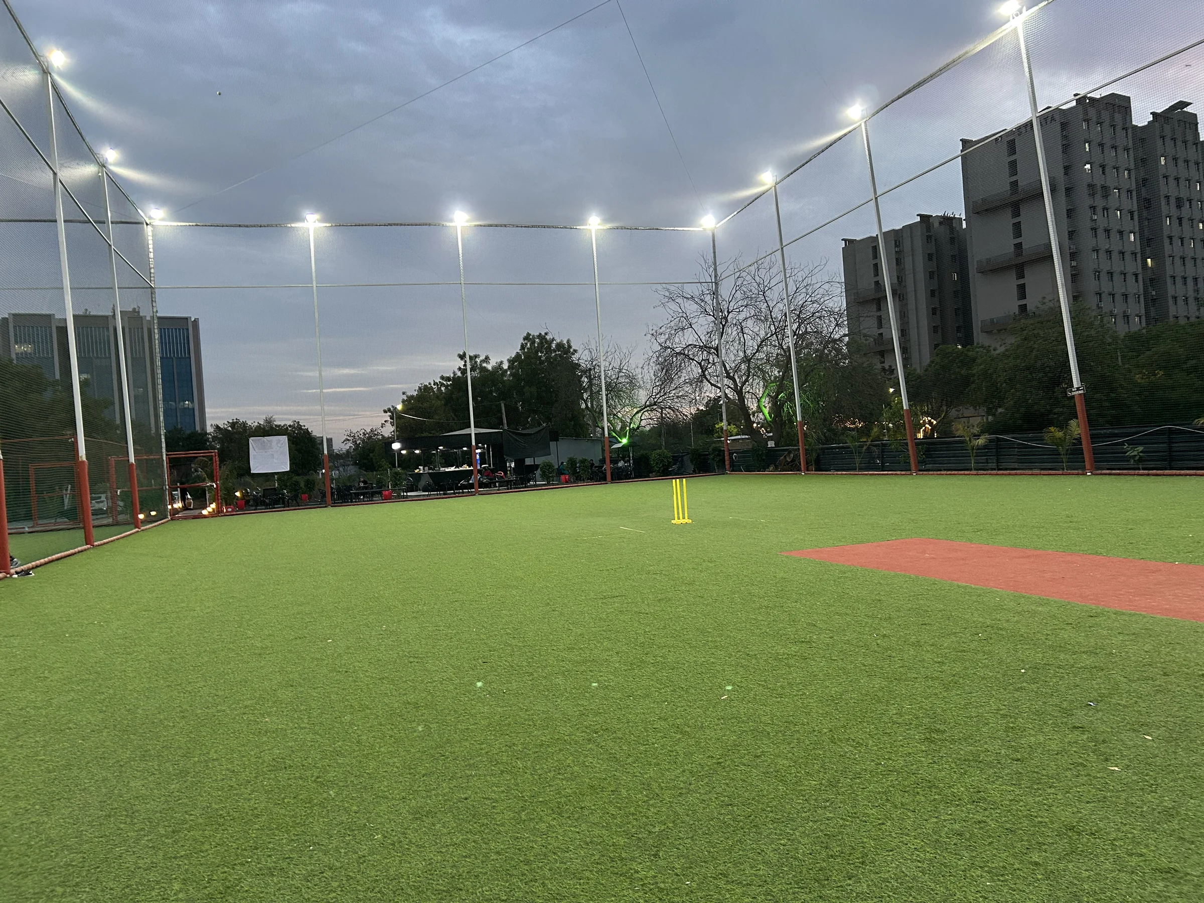 Floodlit cricket turf surrounded by tall cricket netting