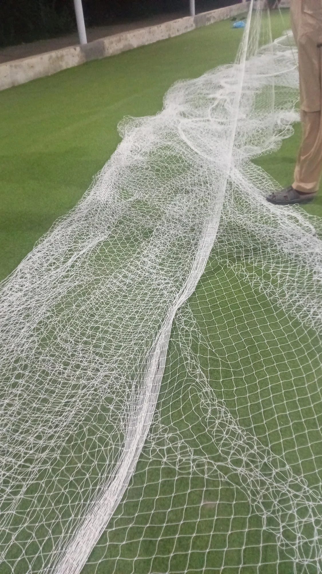 KHS Sports Nets team laying out a knotted cricket net on artificial turf